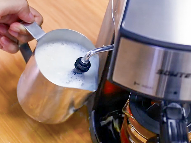 Espumando leche usando la varilla de vapor de la cafetera espresso Sowtech