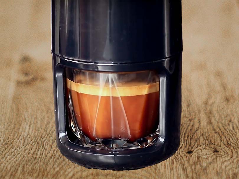 Primer plano de la taza de cristal bajo la cafetera portátil Staresso con un shot de espresso recién extraído
